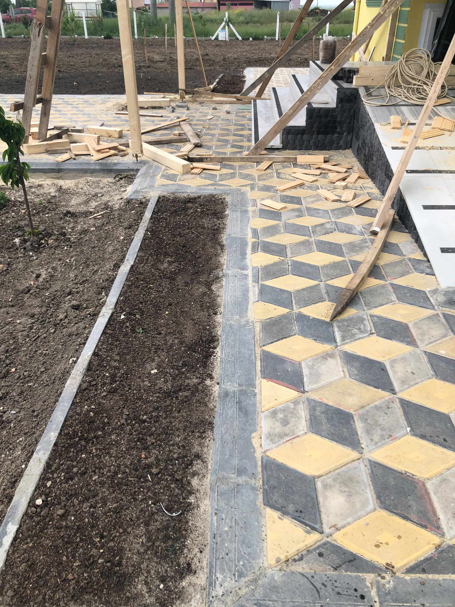 Bahçe alanında sarı gri siyah üç boyutlu küp desenli kilit taşı döşeme montajı