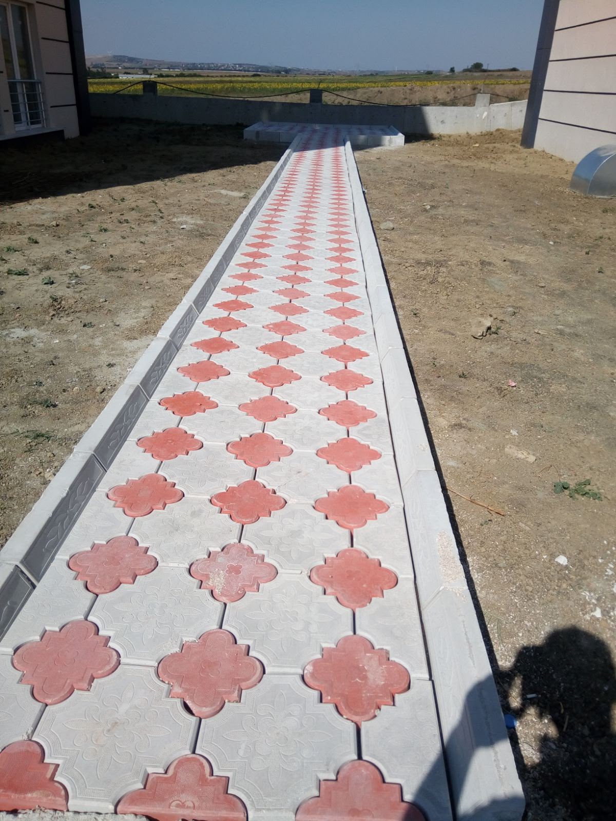 Villa bahçesine uzanan kırmızı gri desenli kilit parke taşı yürüyüş yolu uygulaması