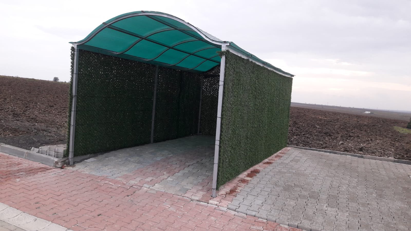 Karakaş Ticaret çim çit kaplamalı garaj sundurması, yeşil polikarbon çatı ve kilitli parke
