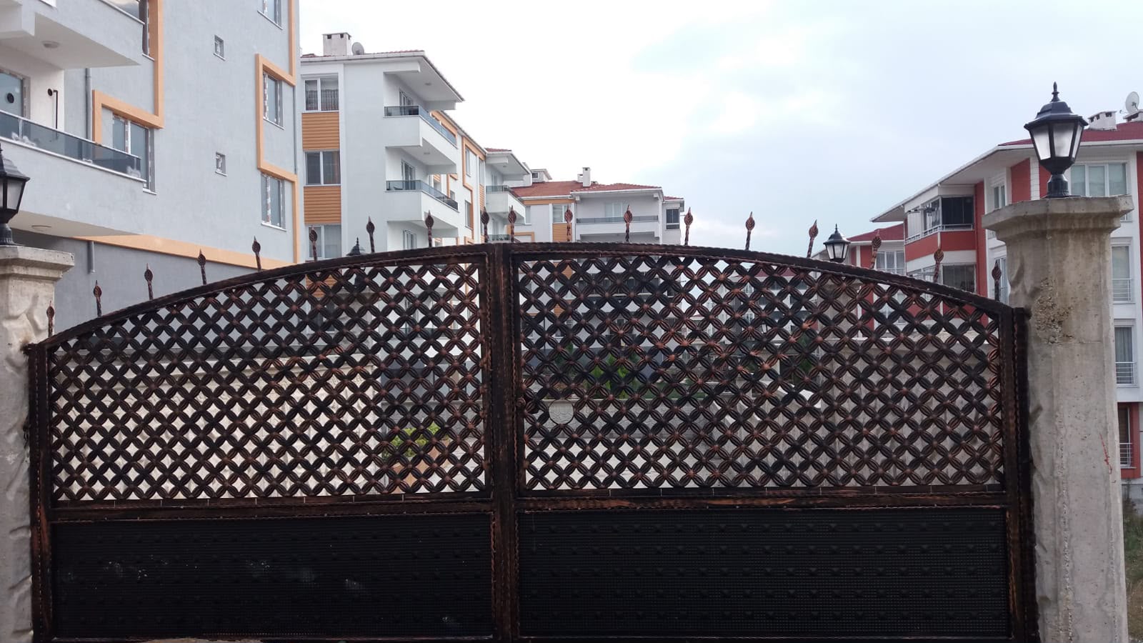 Taş direkli ferforje çift kanat site giriş kapısı ve üstünde bahçe fenerleri