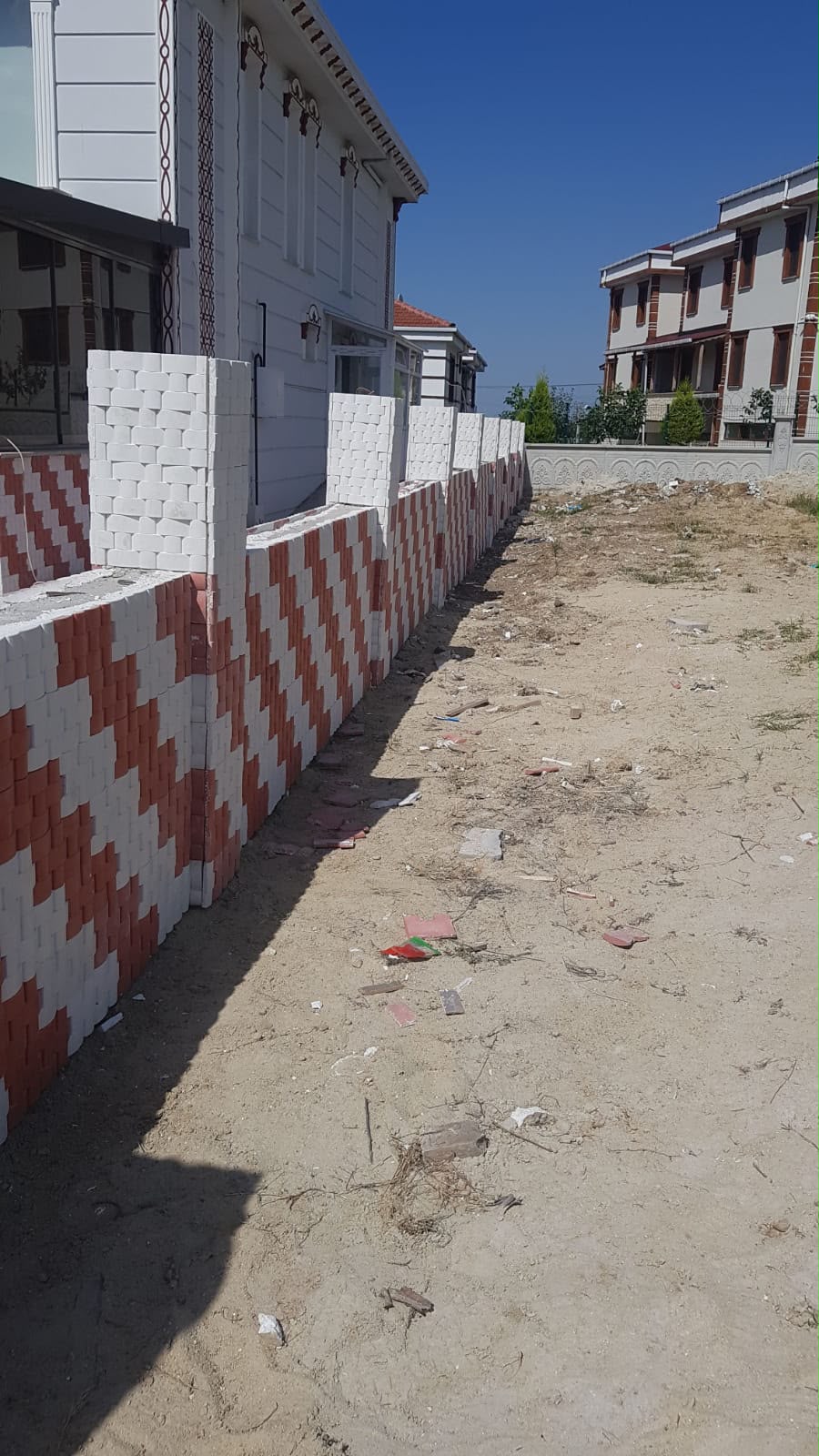 Villa önünde kırmızı beyaz çapraz desenli kilit taşı bahçe çevre duvarı örme