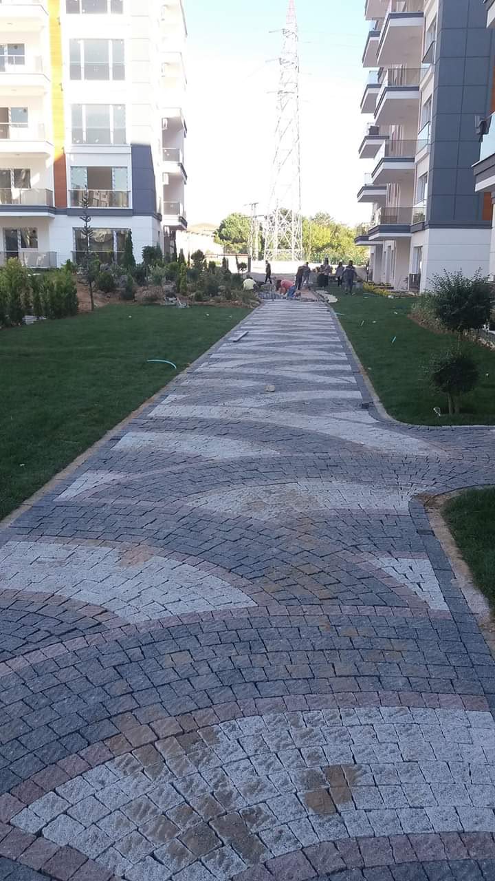 Site içi yeşil alanlar arasında yelpaze desenli granit küp taş yürüyüş yolu