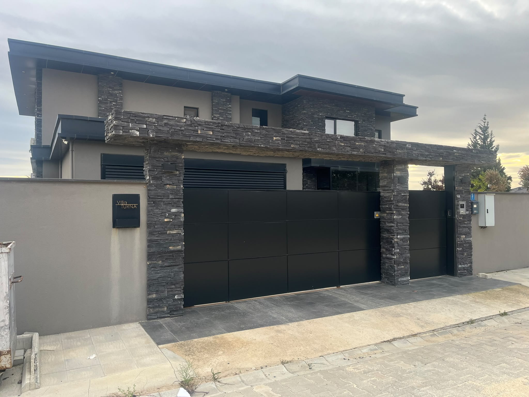 Villa girişinde dekoratif taş kaplama ve antrasit kayar kapı — Karakaş Ticaret
