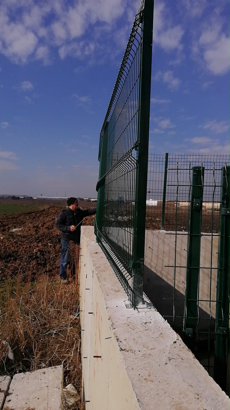 Beton duvar üzerine monte edilen yeşil panel çit sisteminin arazi montaj aşaması