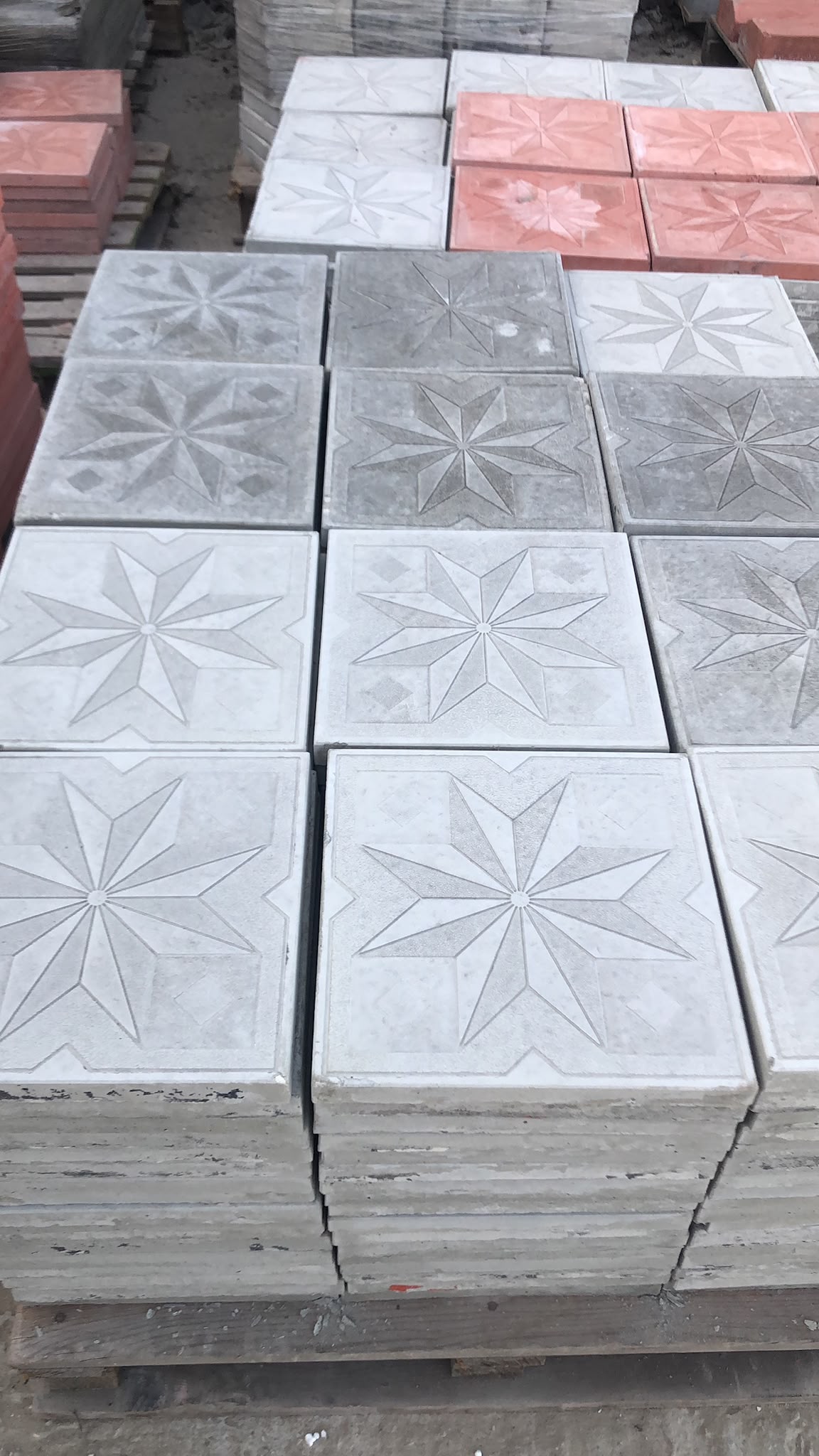 Fabrika stok alanında gri ve kırmızı yıldız desenli karo taş paletleri depo görünümü
